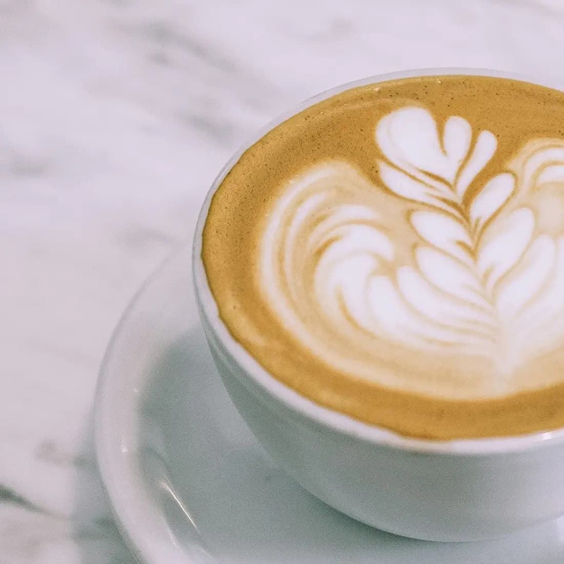Café servi dans une tasse blanche sur marbre, art latte
